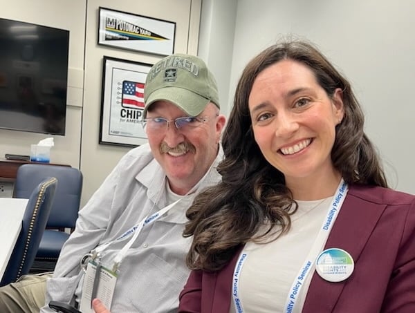 Kim Schreiber and Steve Crumb smile together in a congressional meeting room.