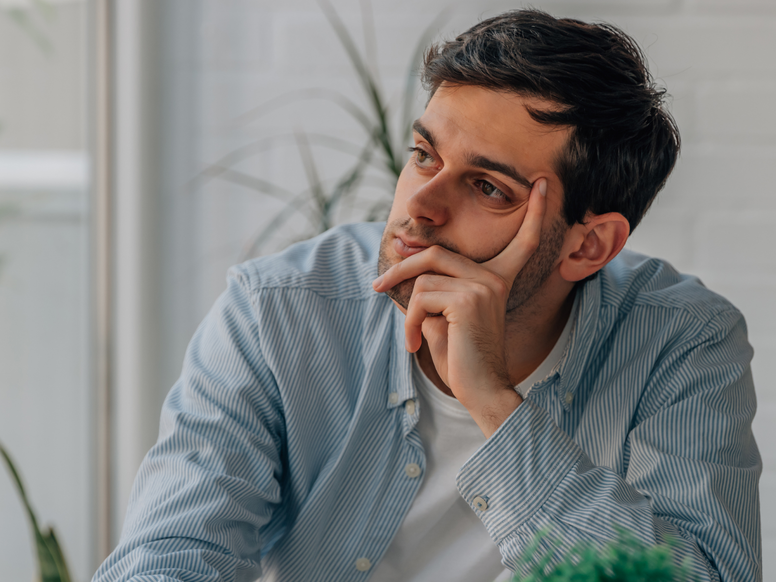 A man leaning his head on his hand and looking into the distance.