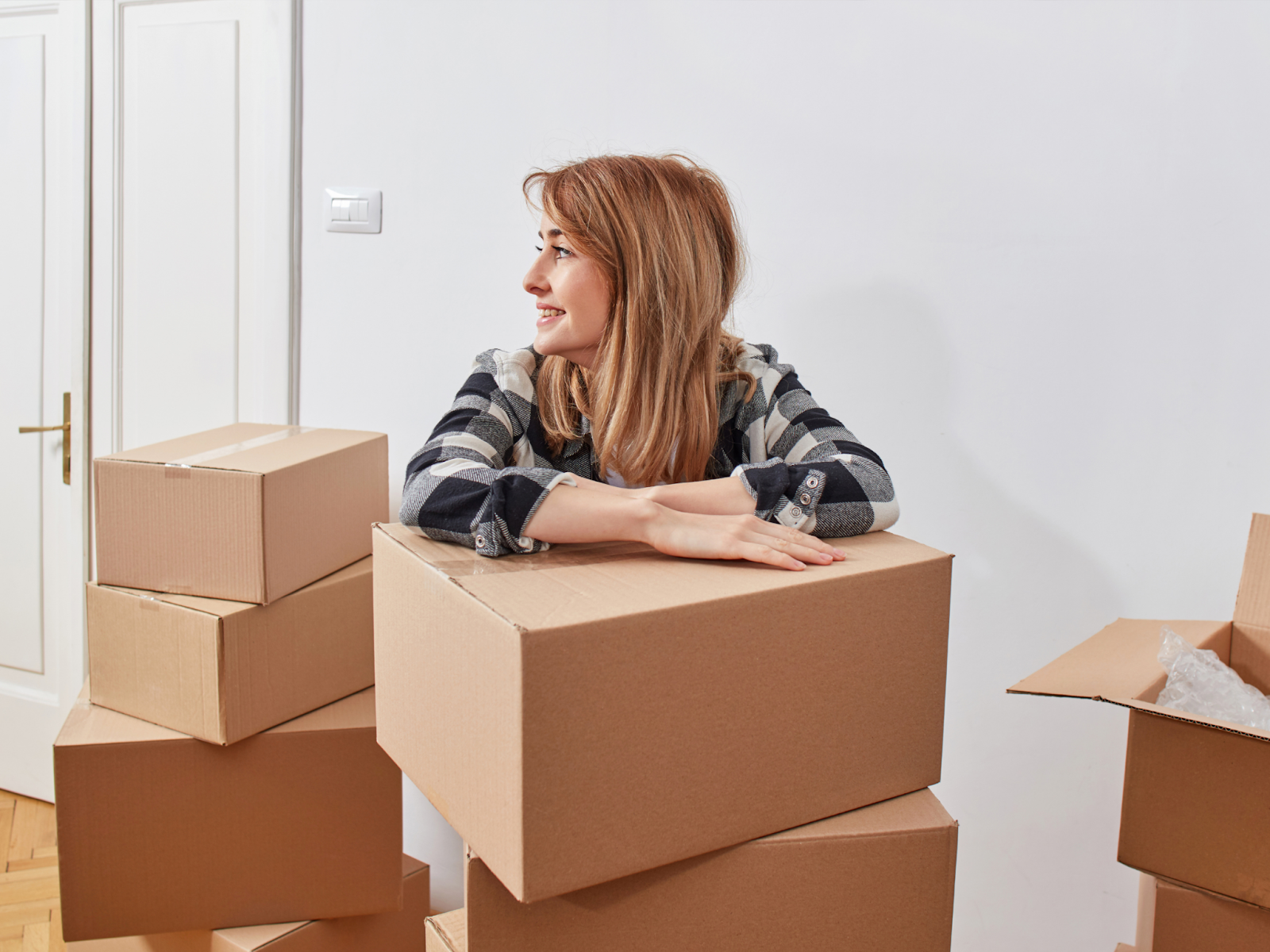 A smiling woman surrounded by packed moving boxes.