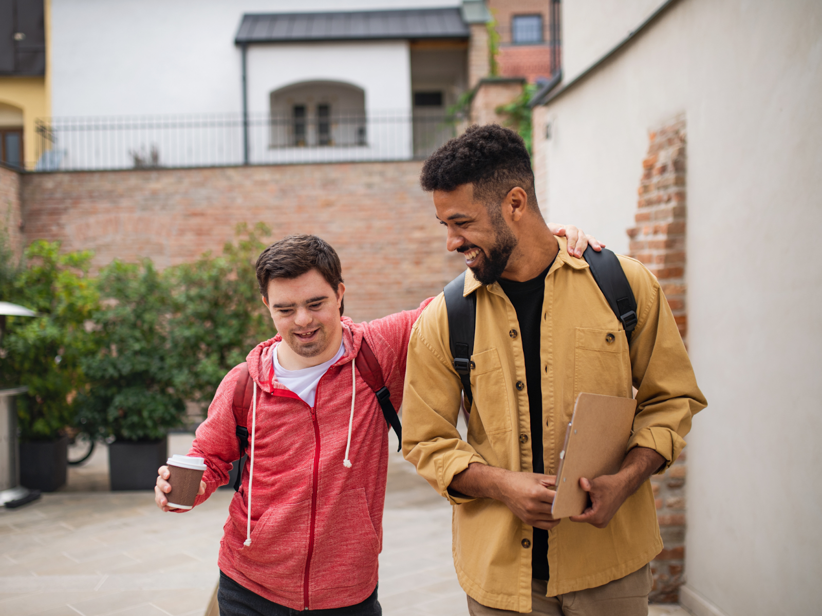 Two friends walking outdoors together and smiling.