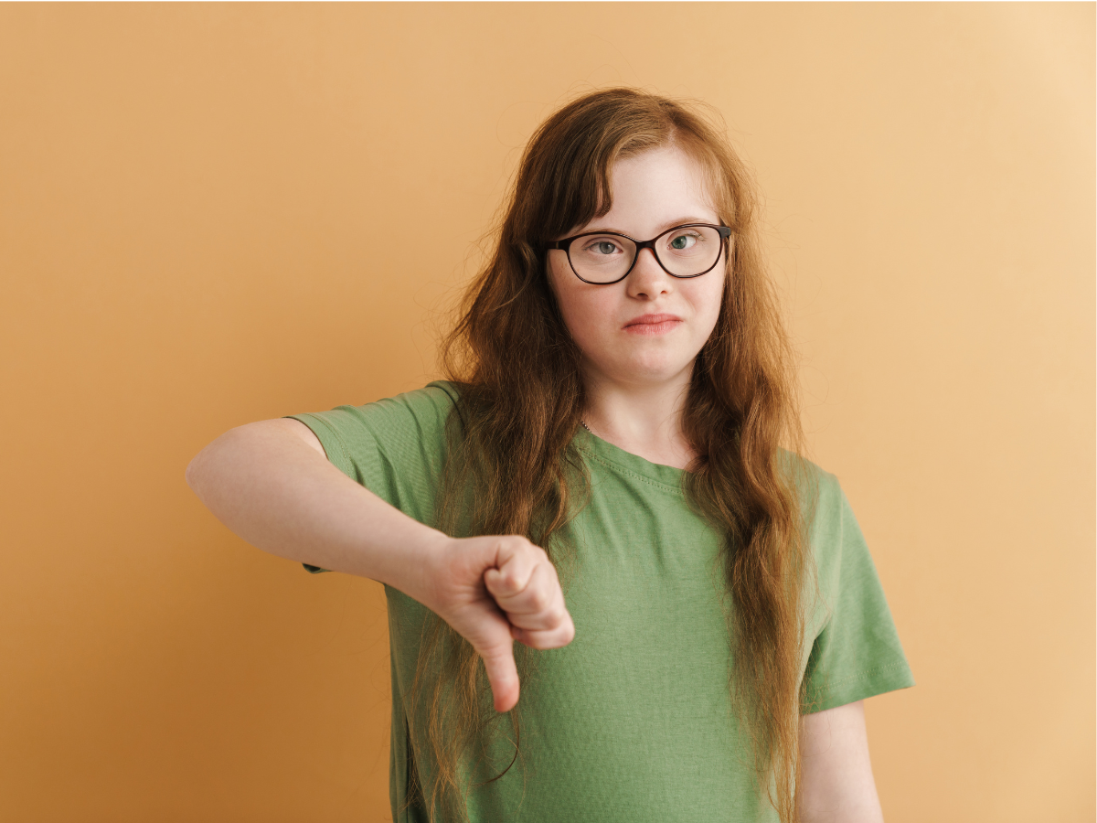 Woman with developmental disability giving thumbs down gesture.