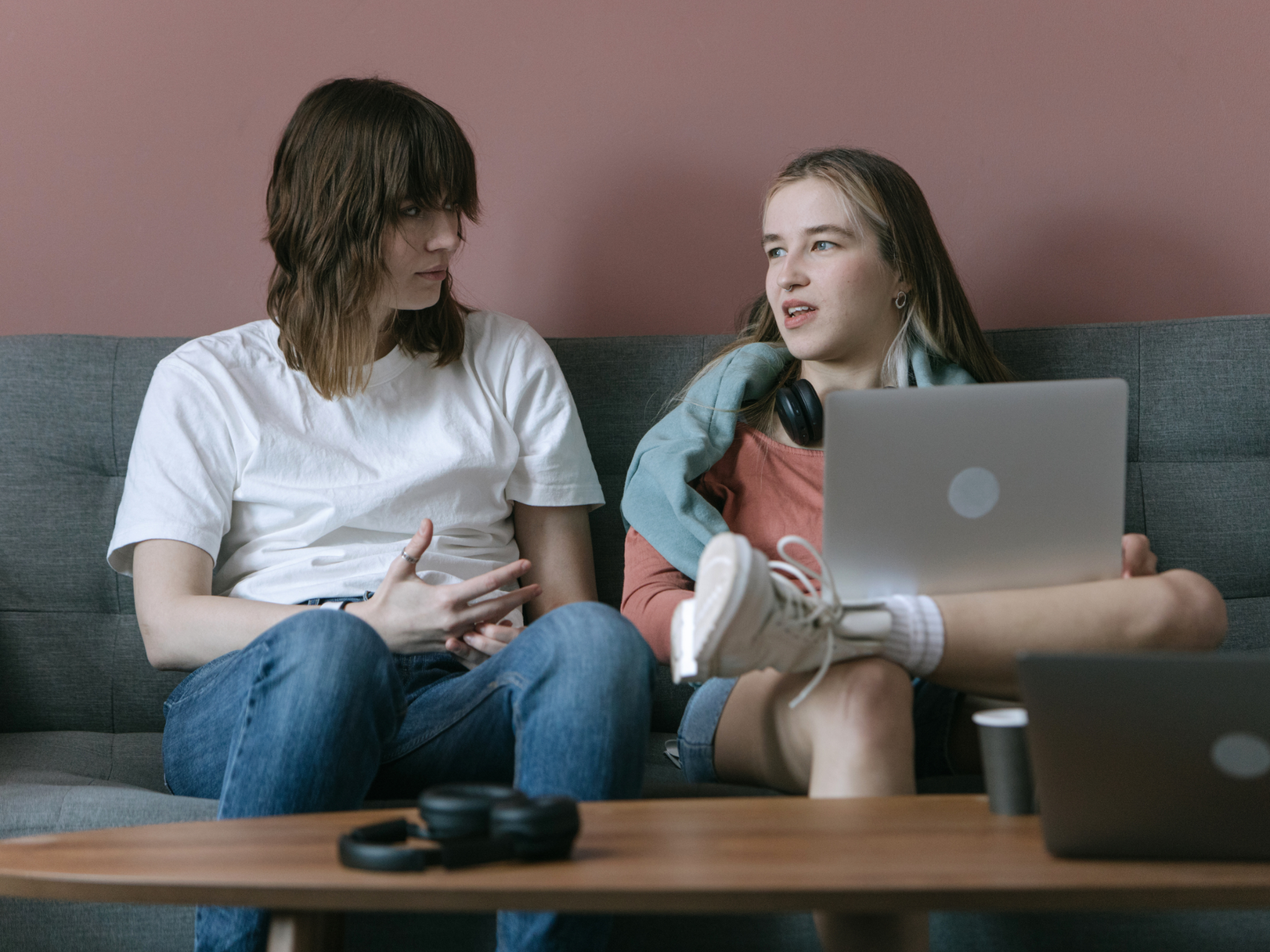 Two women sitting on a couch having a conversation.