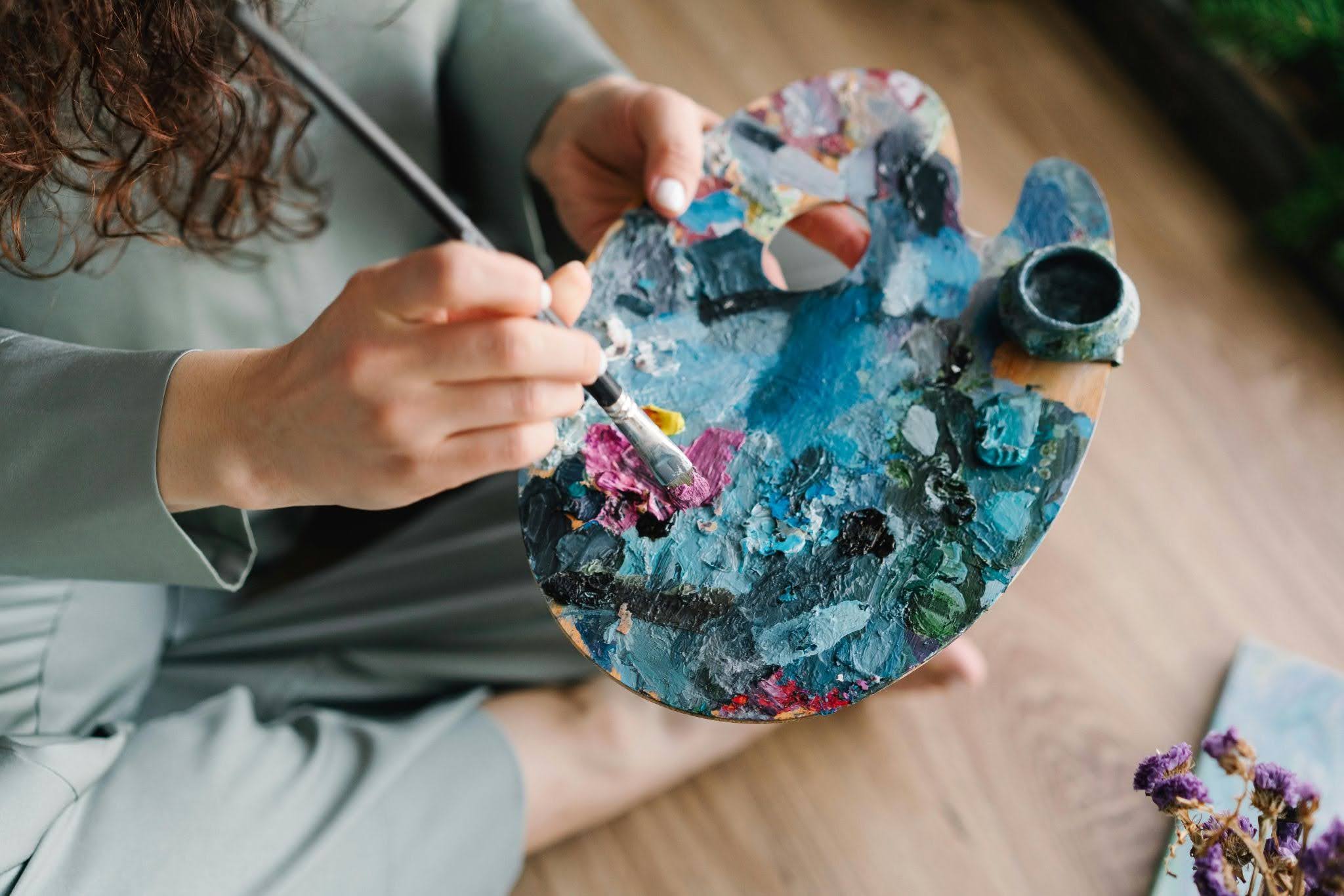 An artist with autism mixing paint on a paint palette.