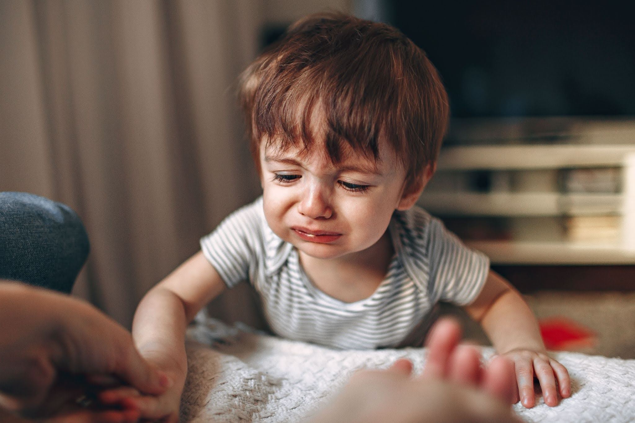 A young child with autism spectrum disorder calms down from a tantrum as a parent gently holds his hand