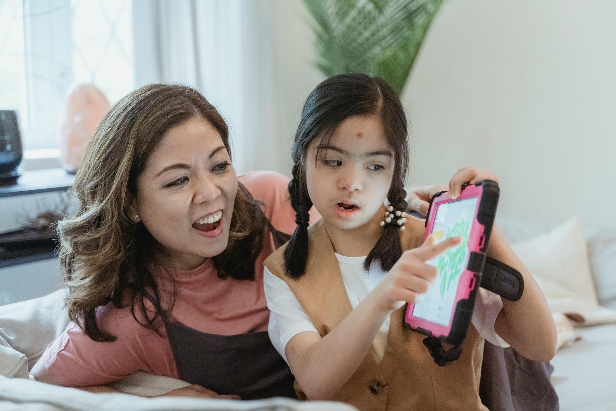 A non-verbal autistic child communicating with her caregiver using an AAC (Augmentative and Alternative Communication Device)