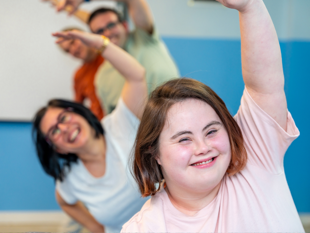 An adult and her family smiling and doing yoga poses together