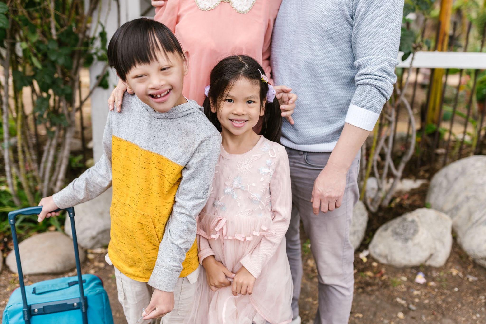 Two children, one of whom has a developmental disability, pose in front of their parents before a family vacation