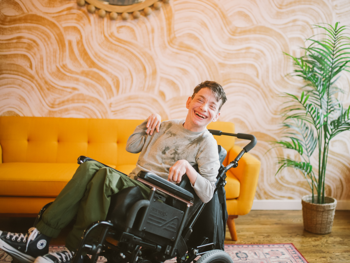 A person with a disability in a wheelchair smiling in a sunny room