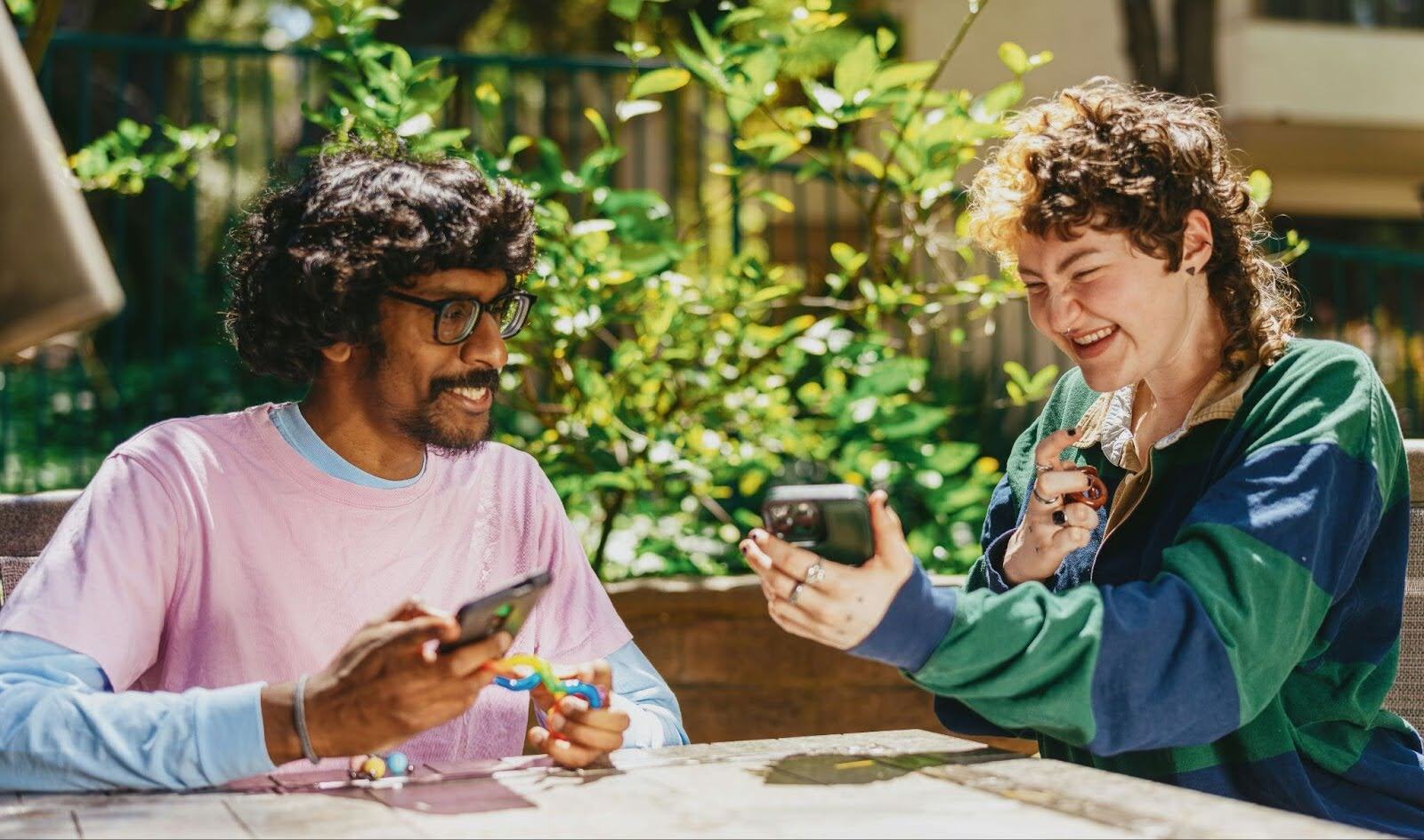 Two people sitting at a table sharing insights on cellphone