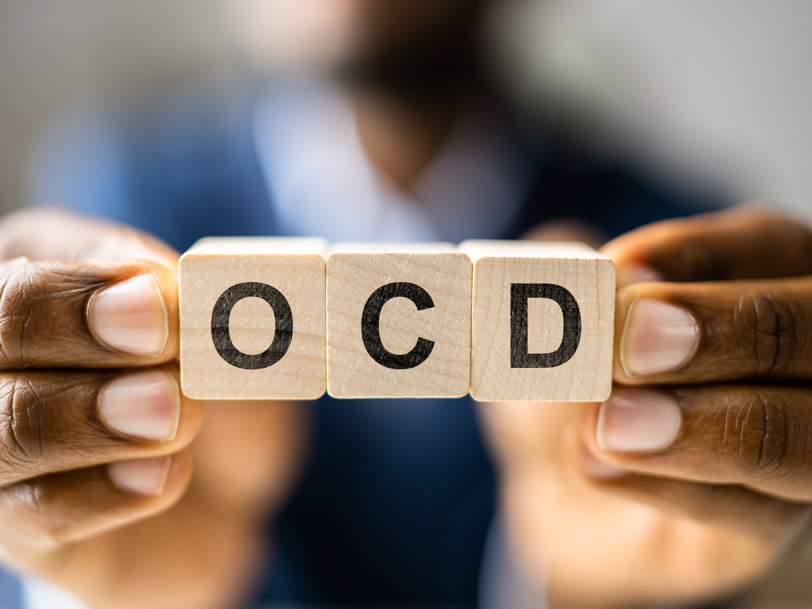 A person holding letter blocks that spell OCD