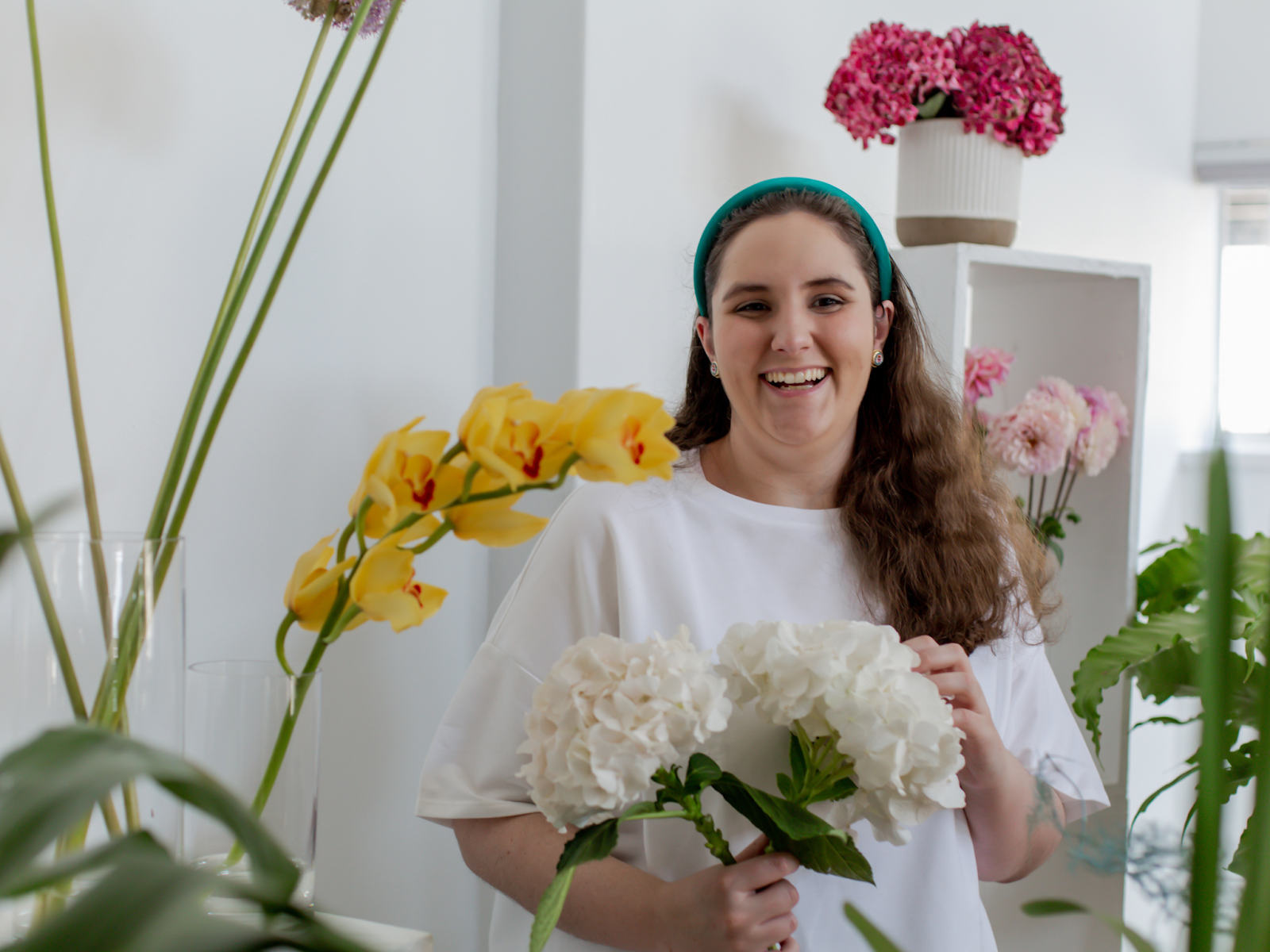 An adult woman with autism smiling and holding flowers in a flower shop