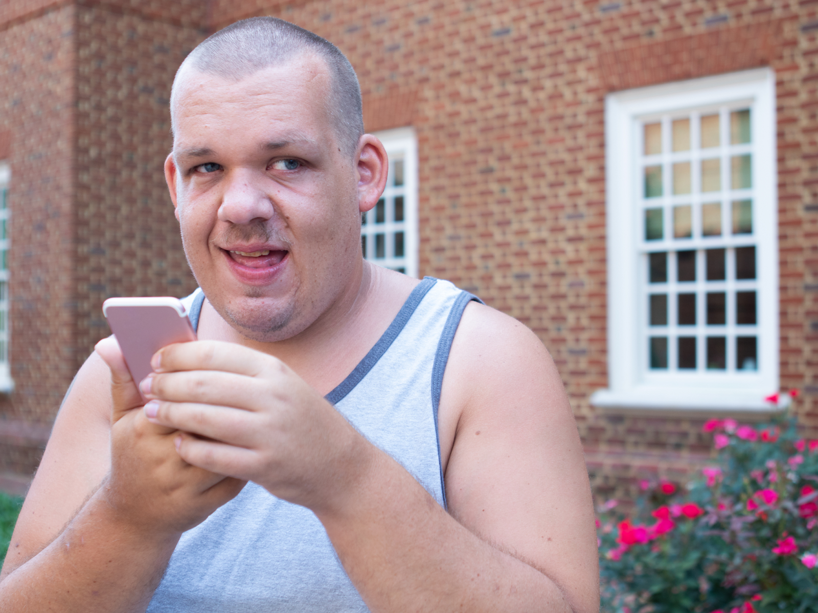 A man holds his smartphone outside of a red-brick building