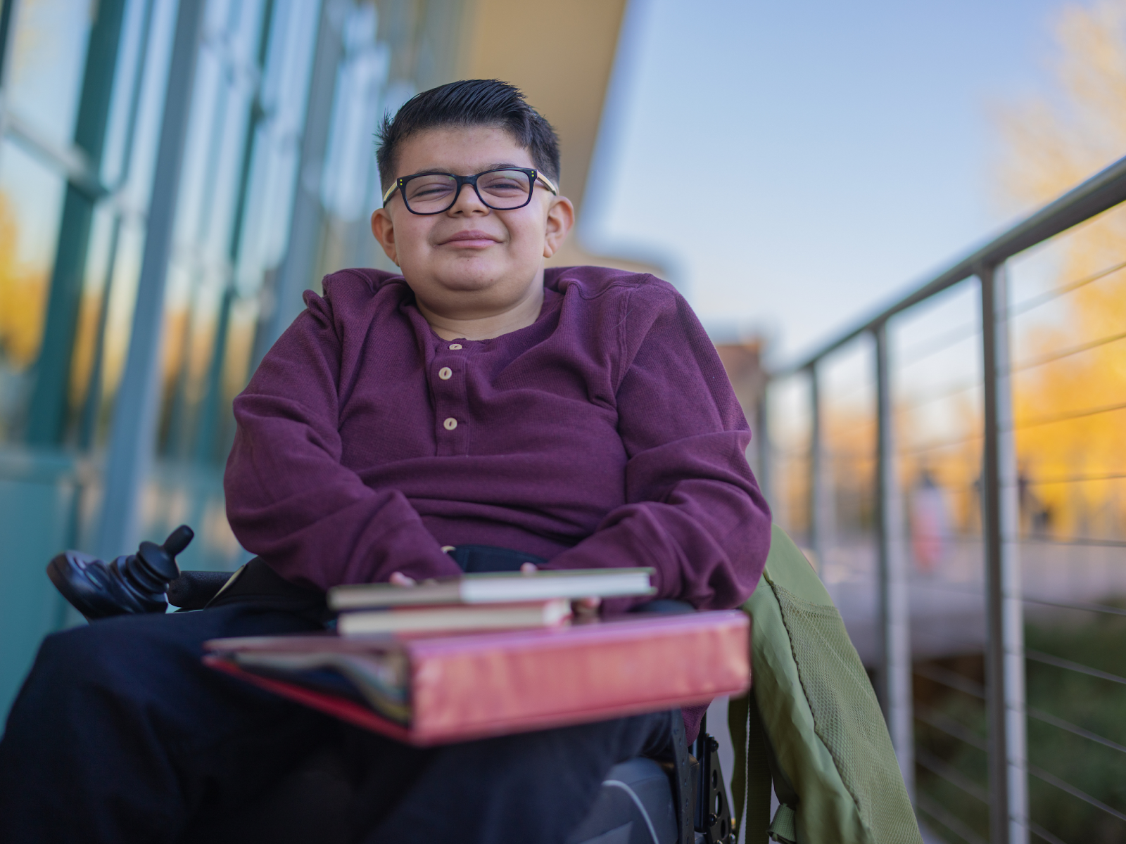 A person in an electric wheelchair holding books and a binder