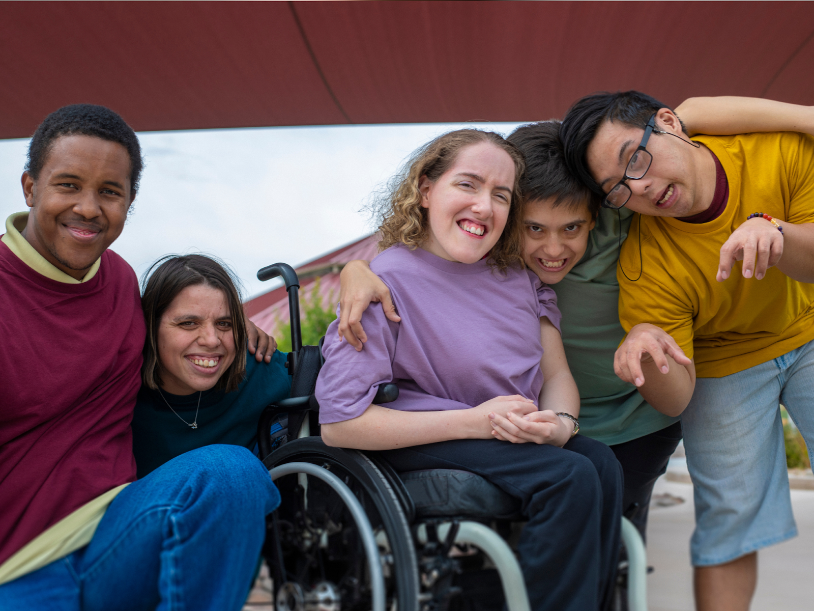 Five individuals with a variety of developmental disabilities gather for a jovial picture