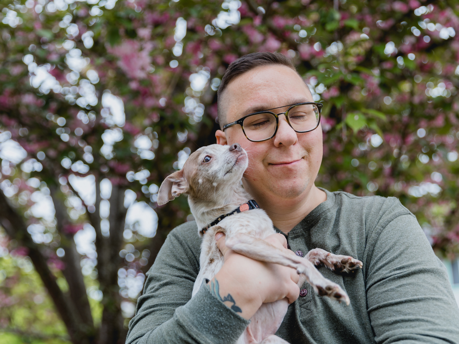 An autistic man lovingly holds his service dog against his chest and face.