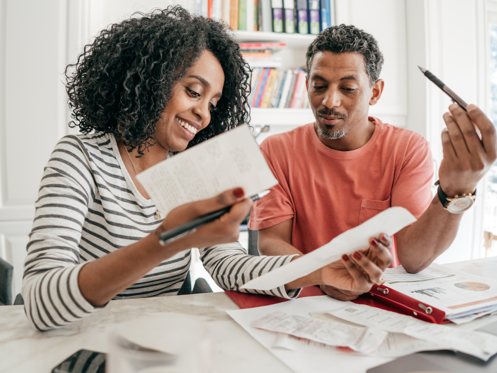 Two adults sitting at a table and smiling while going over financial documents.