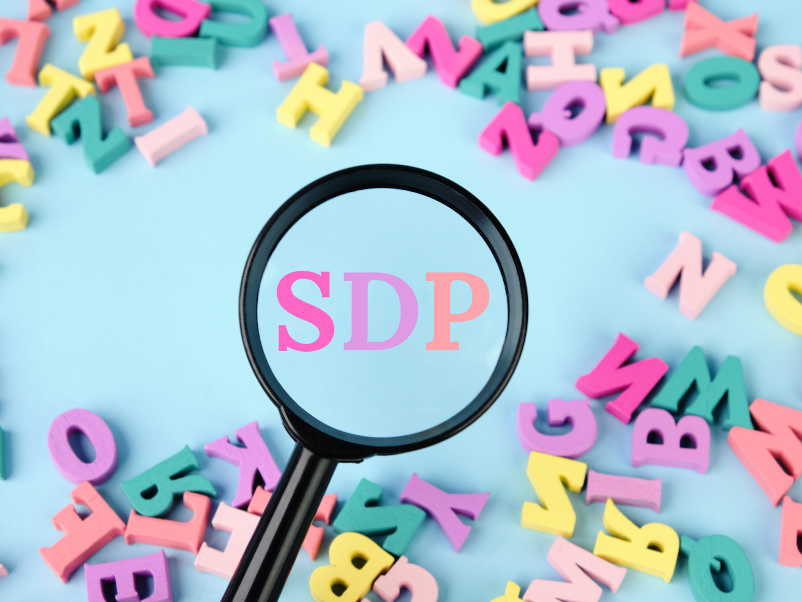 A blue surface covered in colorful letter blocks with a magnifying glass surrounding the letters SDP.