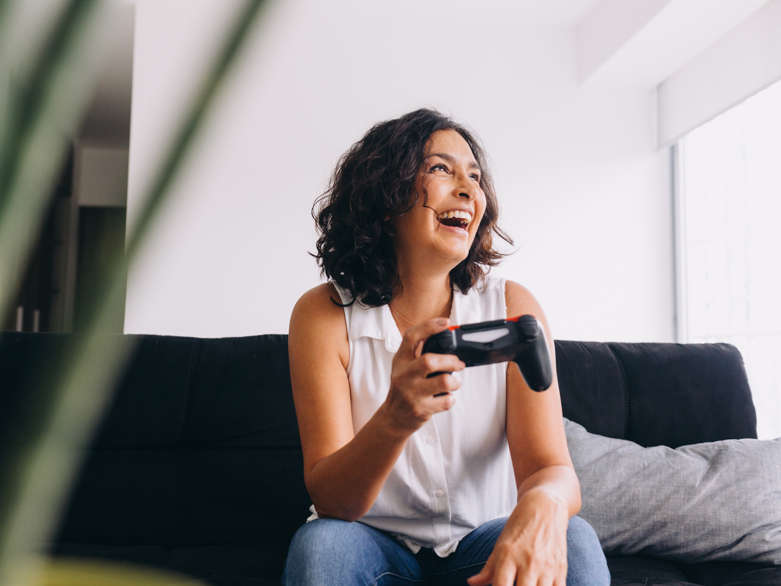 Adult sitting on a couch smiling and holding a game console controller