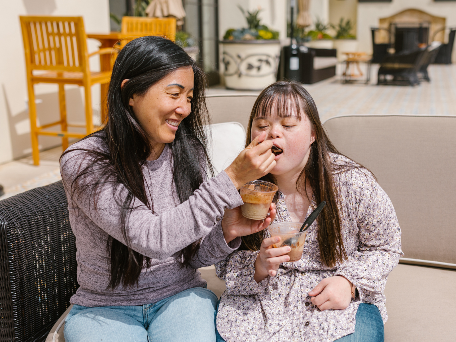 A mother smiling while serving her daughter a bite of food.
