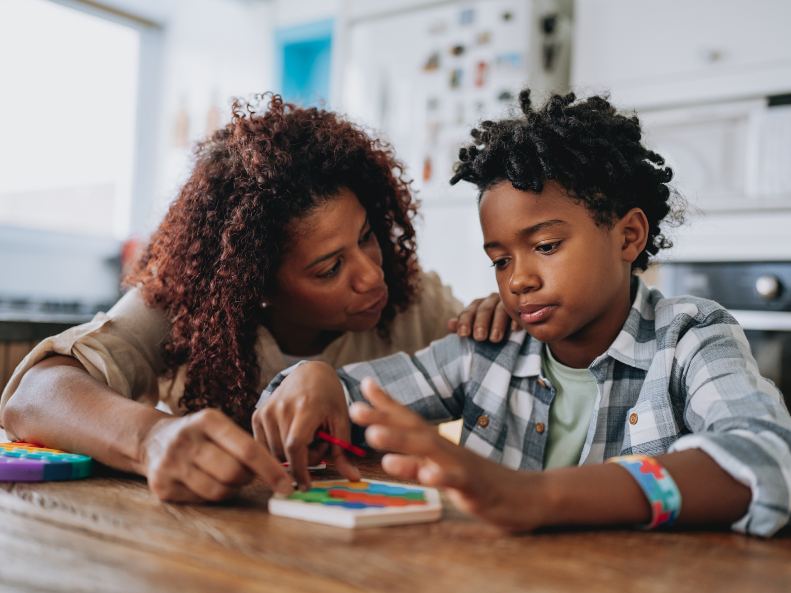 A mother and child sitting at a table doing an activity together.