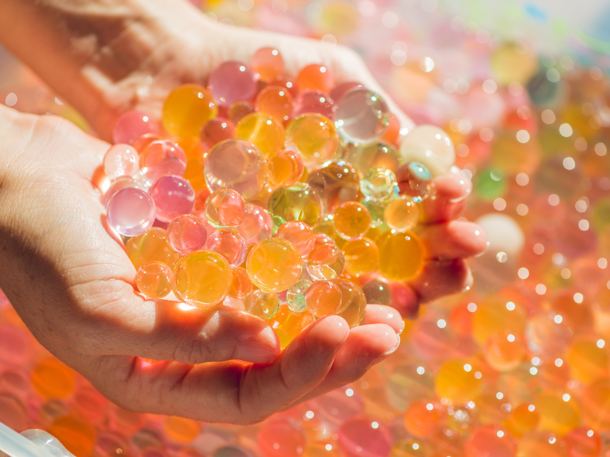 A sensory activity: Two hands holding many colorful marbles