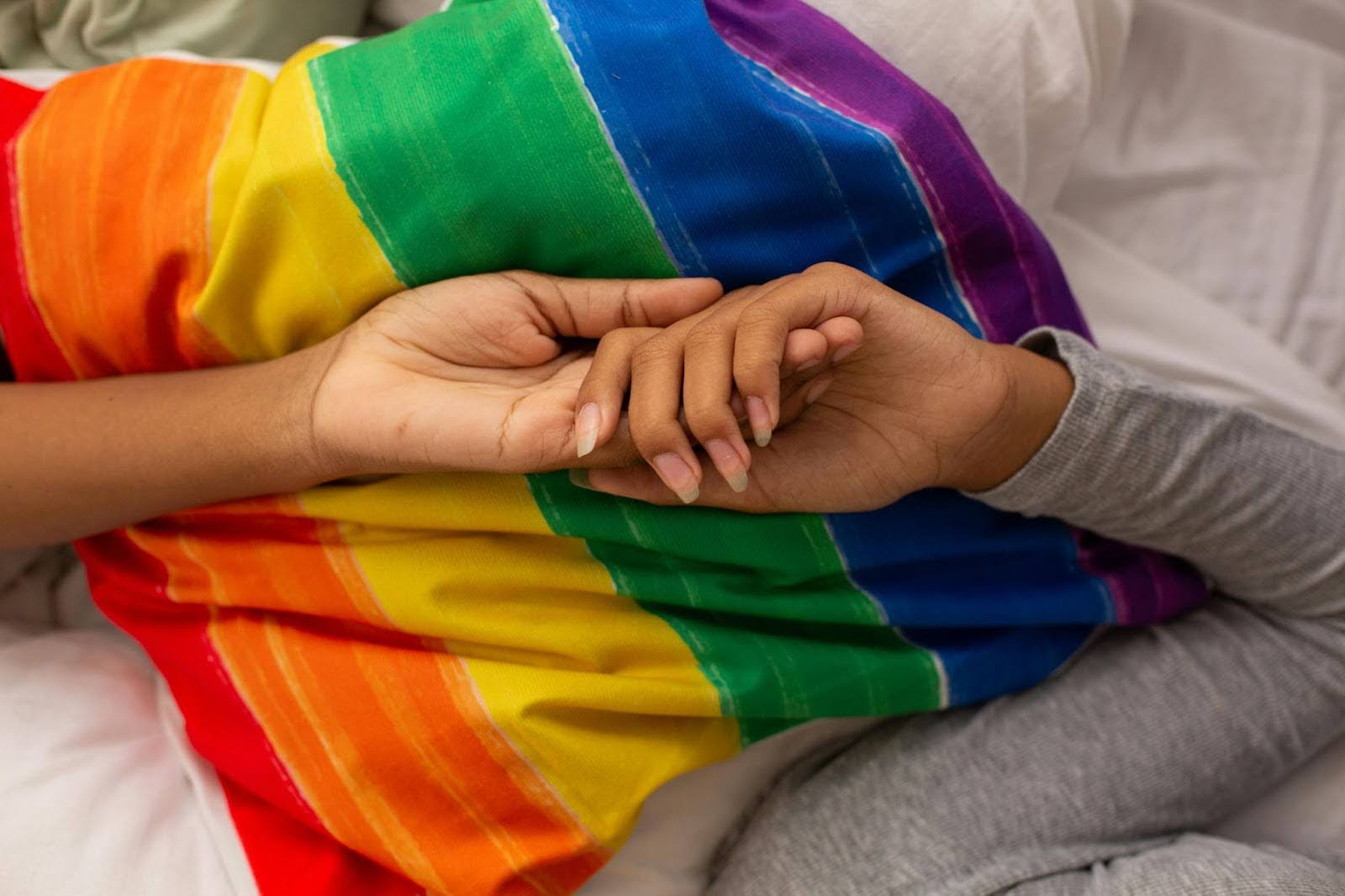 Holding hands in front of a Pride Flag