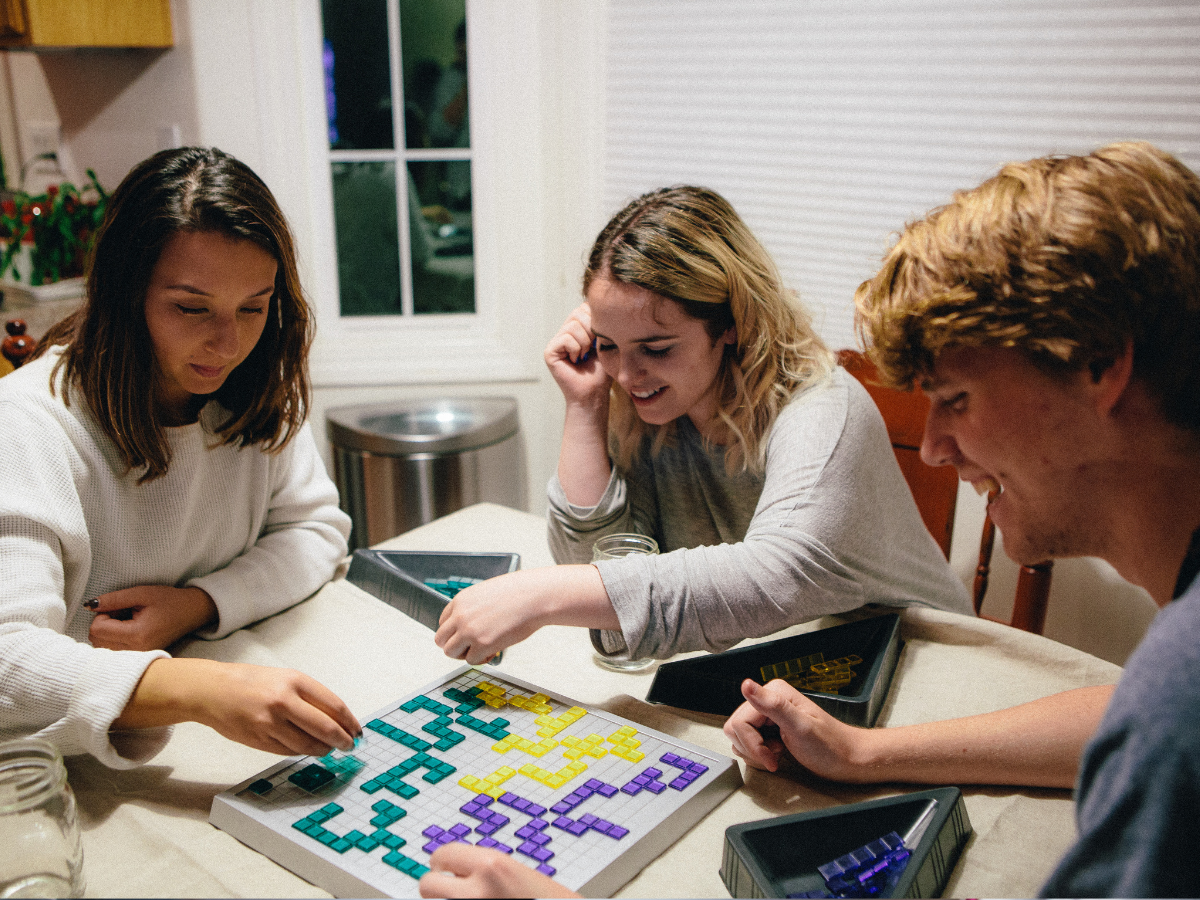 Three adults smiling and playing a board game