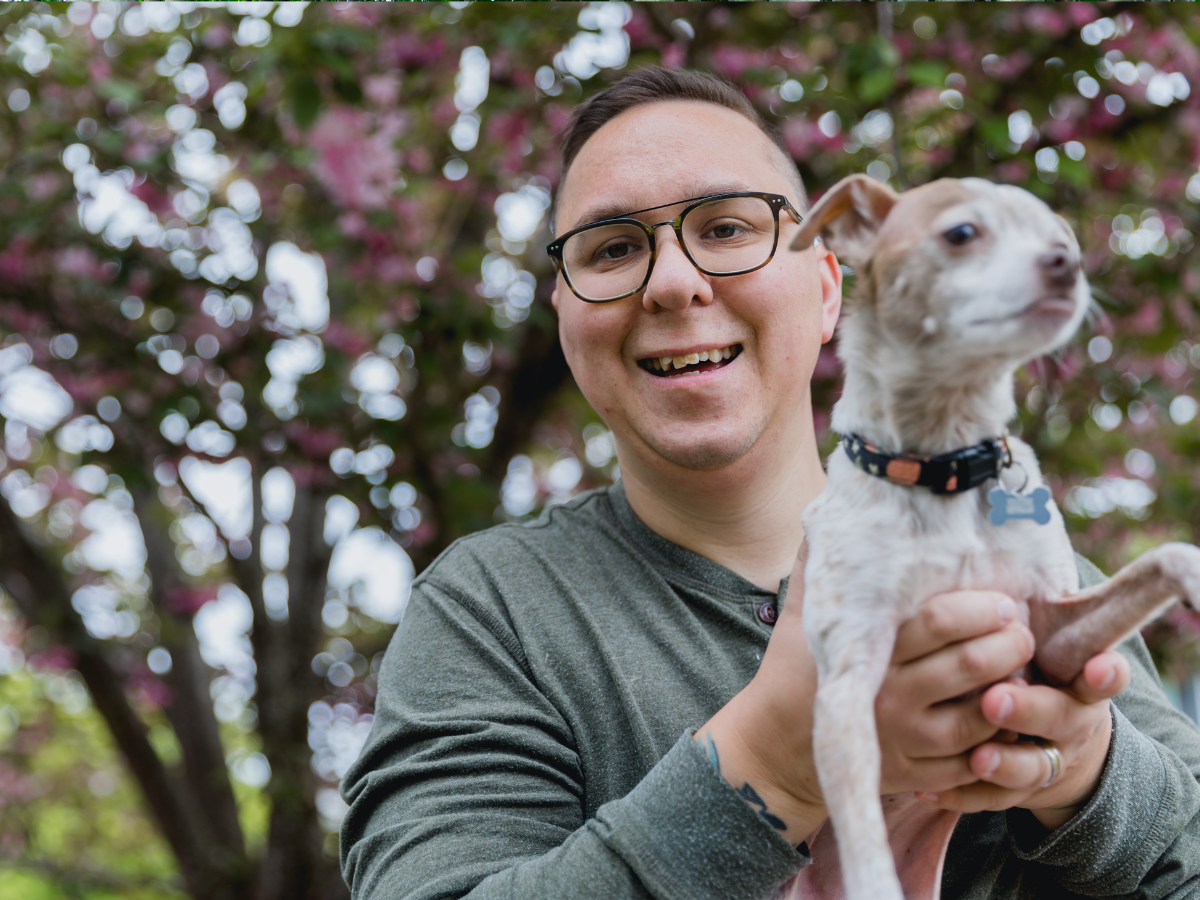 Autistic adult smiling and holding dog