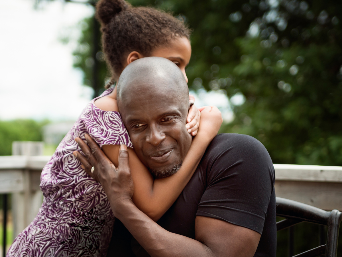 Man sitting and being hugged by a young girl