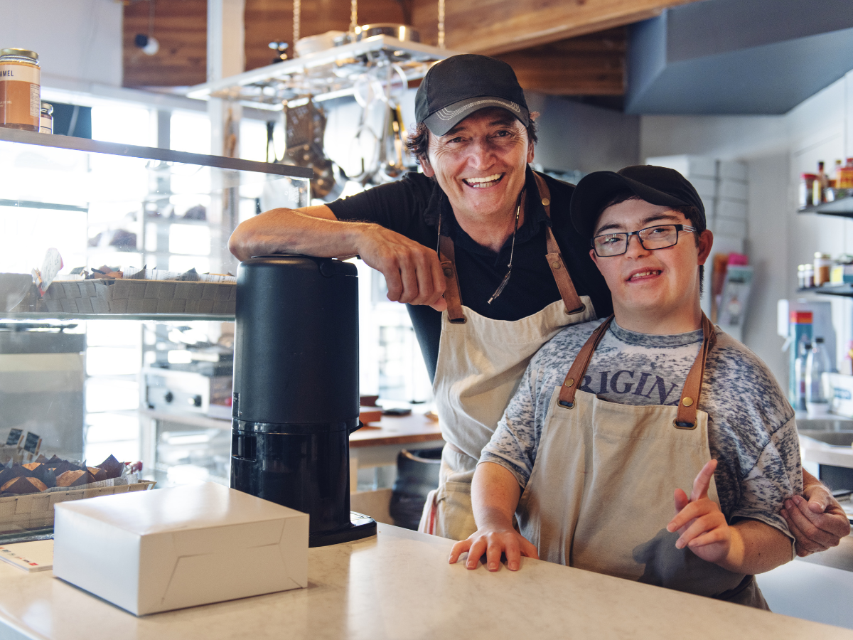 Two people in a work environment looking happily at the camera