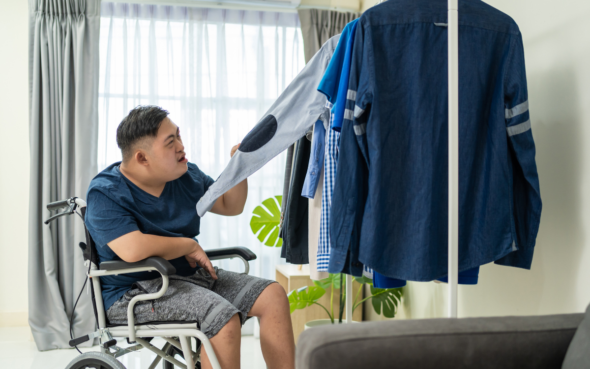 A man with a disability looks through clothes on a rack