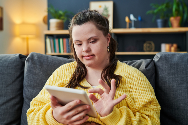 A woman with Down Syndrome scrolls on a tablet