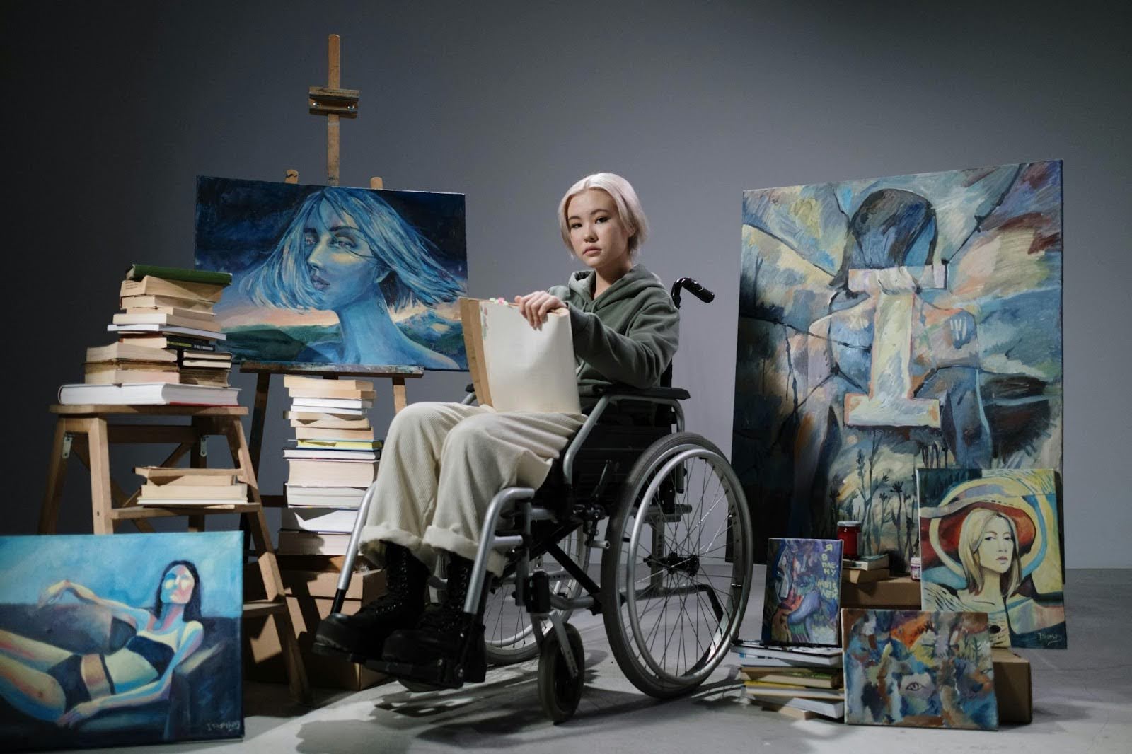 A person in a wheelchair surrounded by artwork and paintings