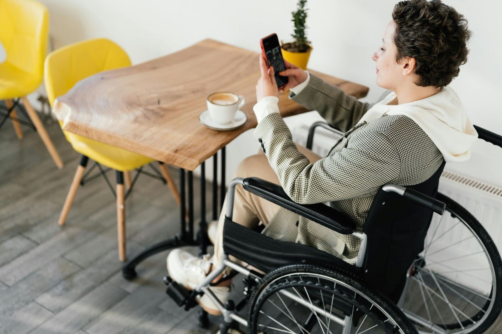 A man in a wheelchair sits at a table in a cafe