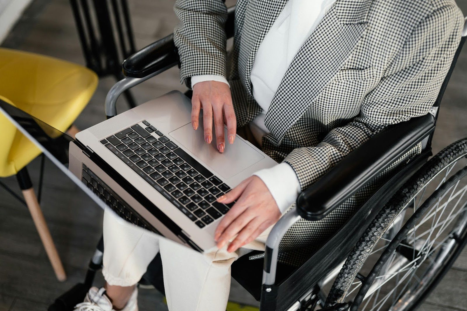 A man in a wheelchair types on a laptop