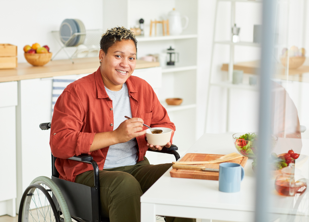 A person in a wheelchair sits at a table eating