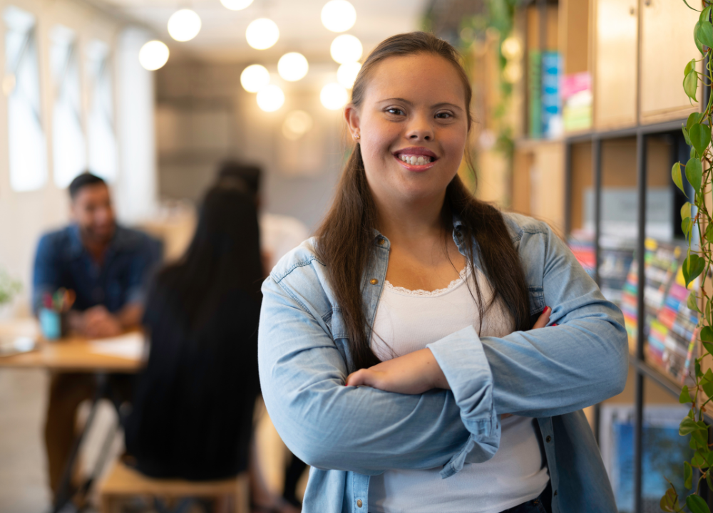 A woman with Down Syndrome folds her arms and smiles