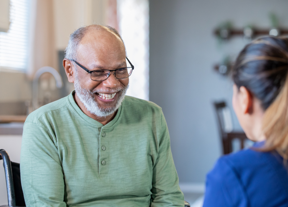 A man sitting at a table smiles at a nurse