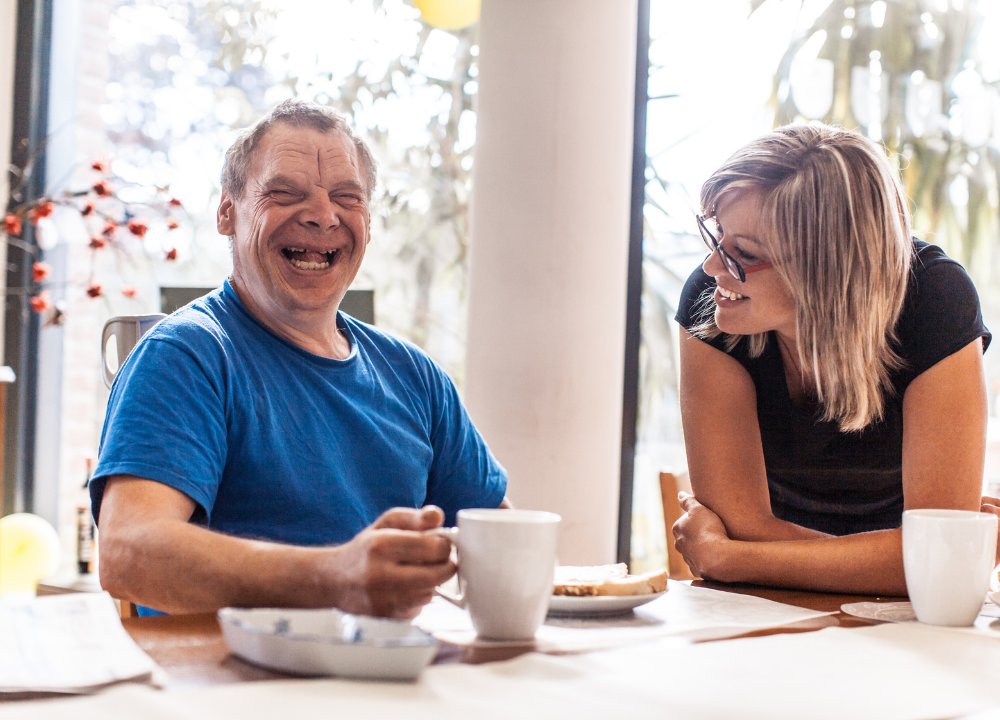 Two people laugh at a table
