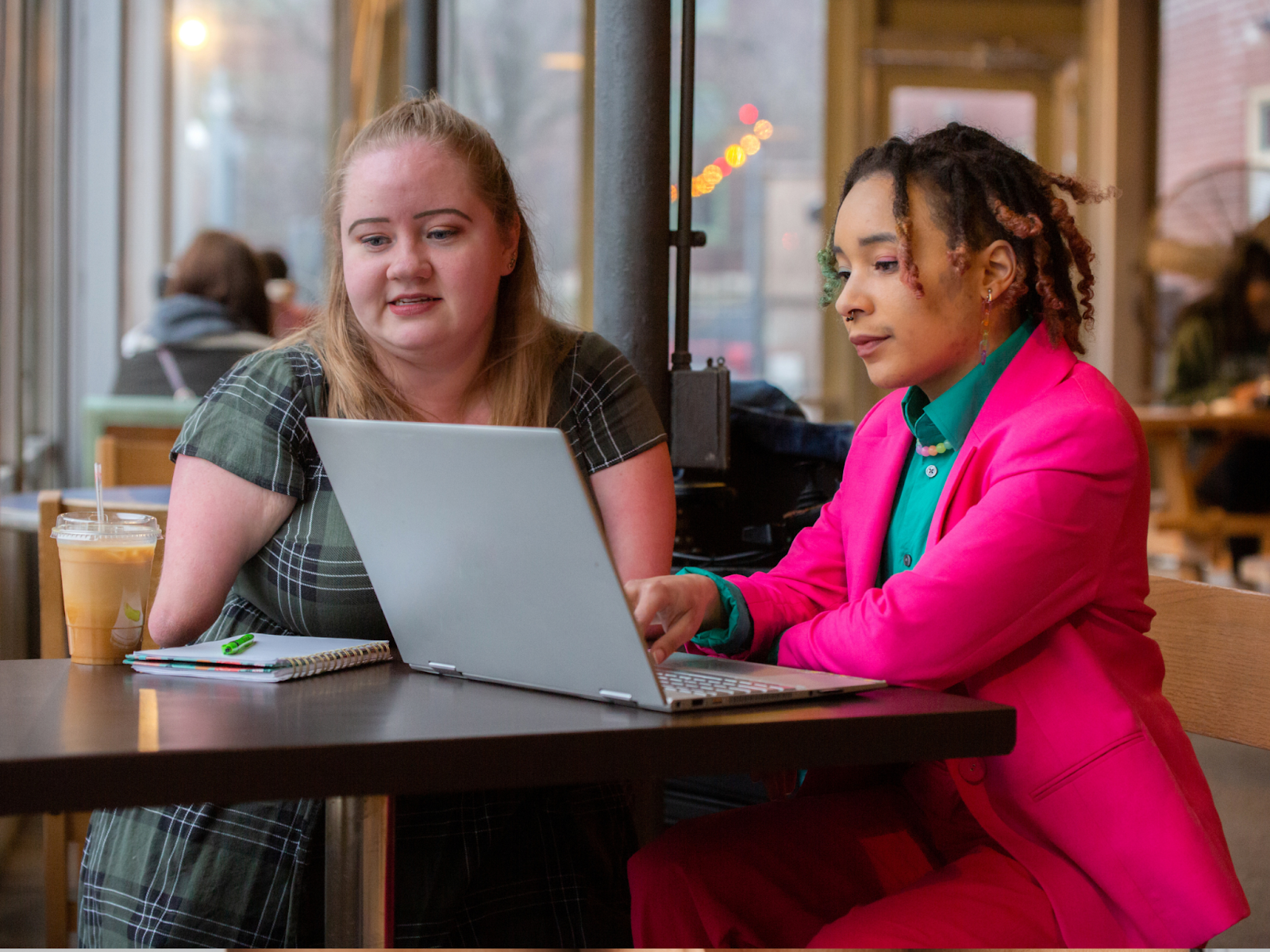 A woman and her case manager sit together at a table and review program plans over a laptop